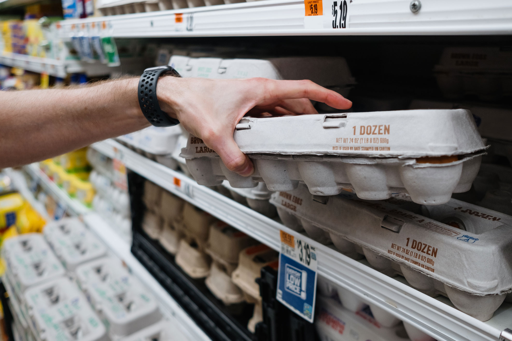 a customer picks up a carton of eggs at the grocery story